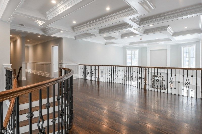 Wooden-floored upper level with a curved railing, decorative ceiling, and windows.