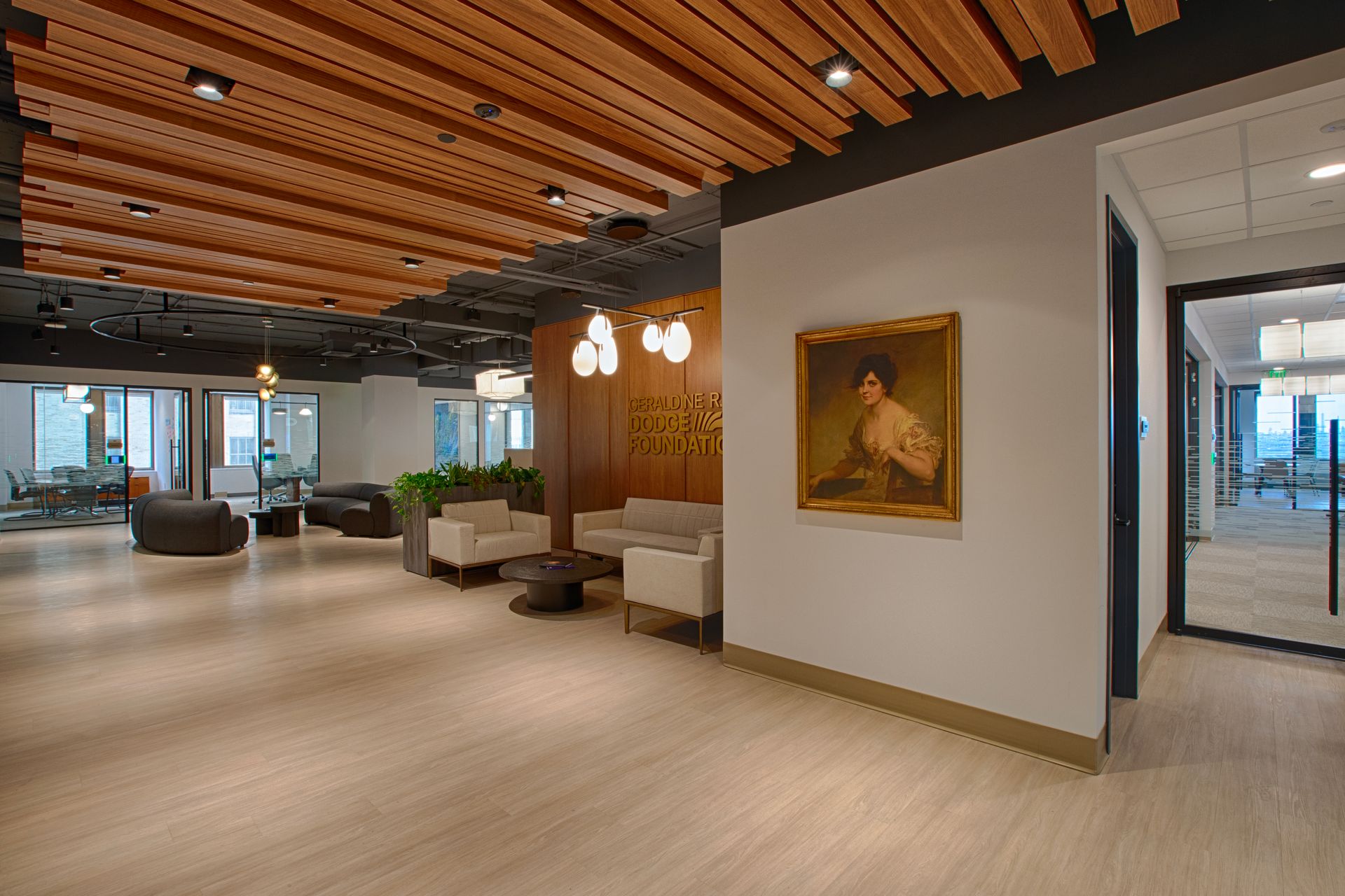 Lobby with light wood floor, ceiling with wood slats, seating areas, and a framed painting.