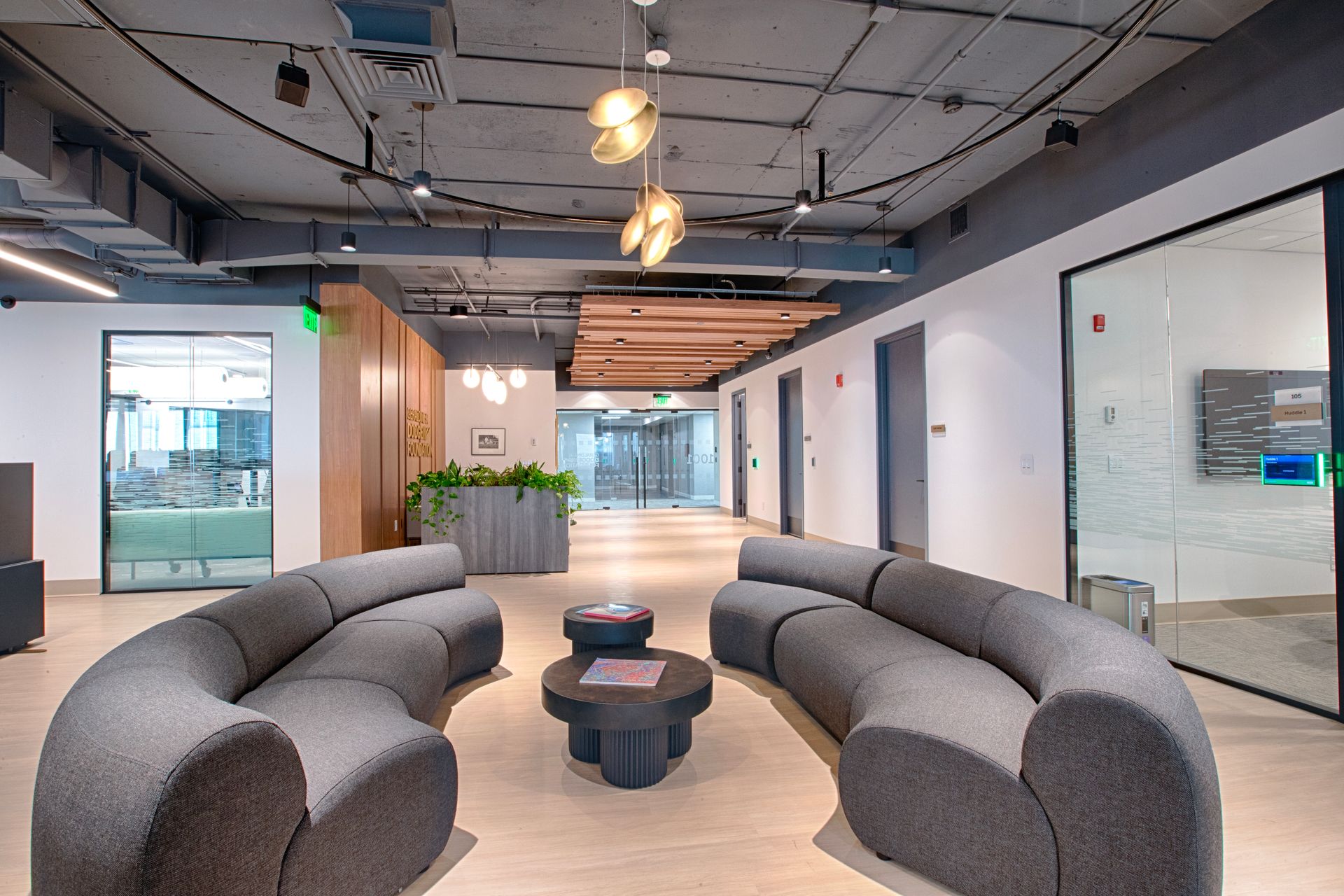 Modern office lobby with curved sofas, central coffee table, and overhead lighting.