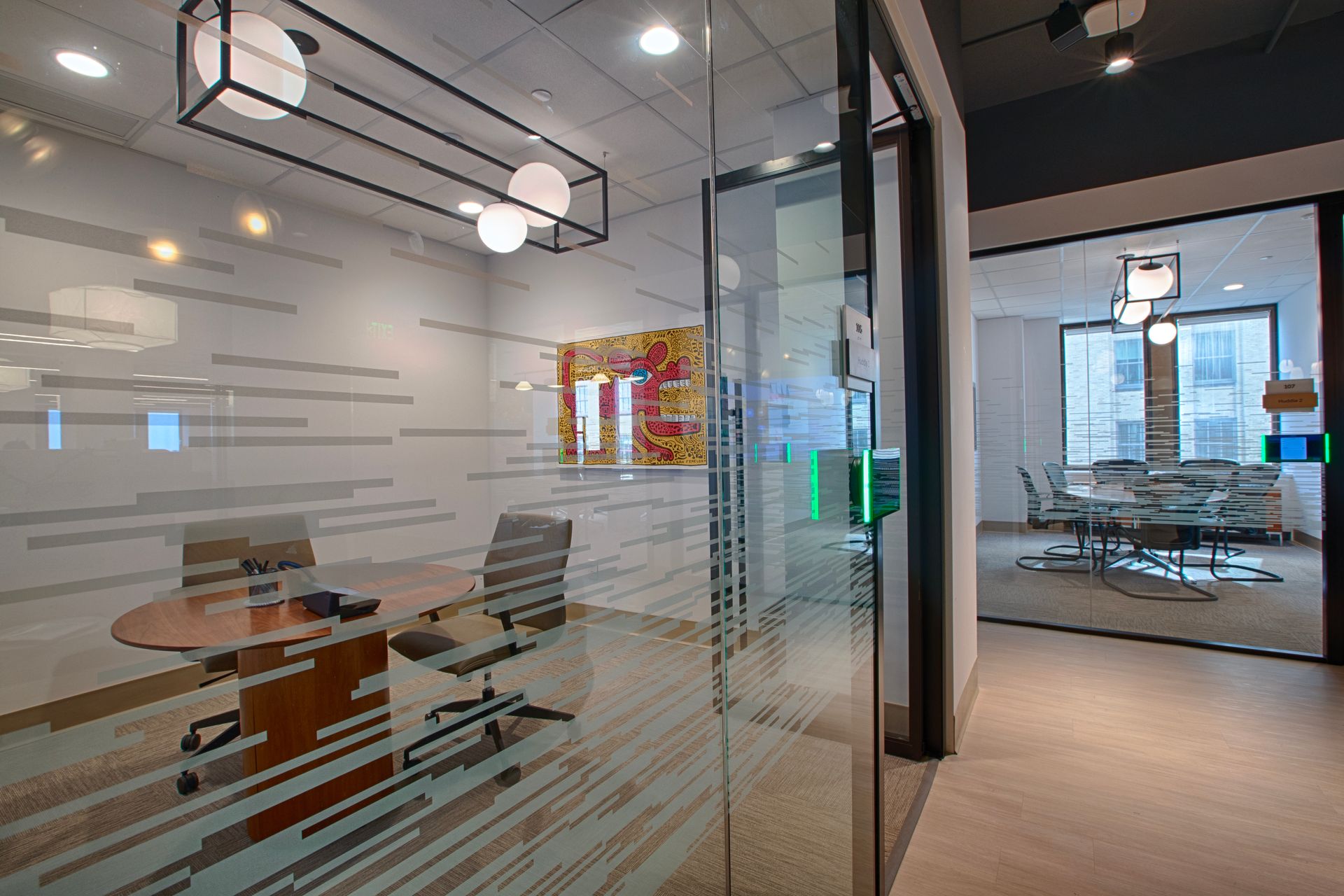 Modern office interior with glass walls, conference tables, and city views.