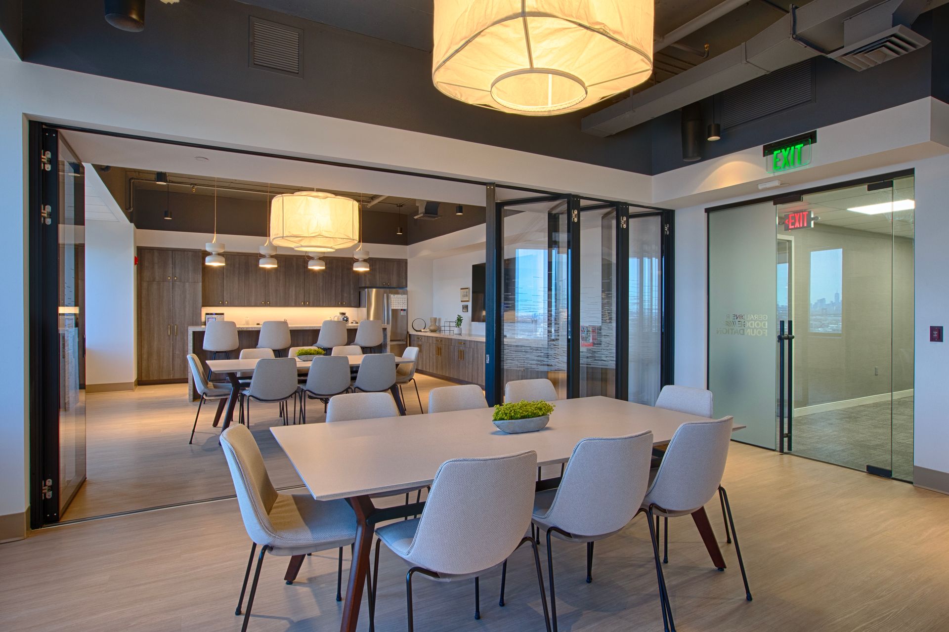 Modern office dining area with long table, chairs, and pendant lighting.