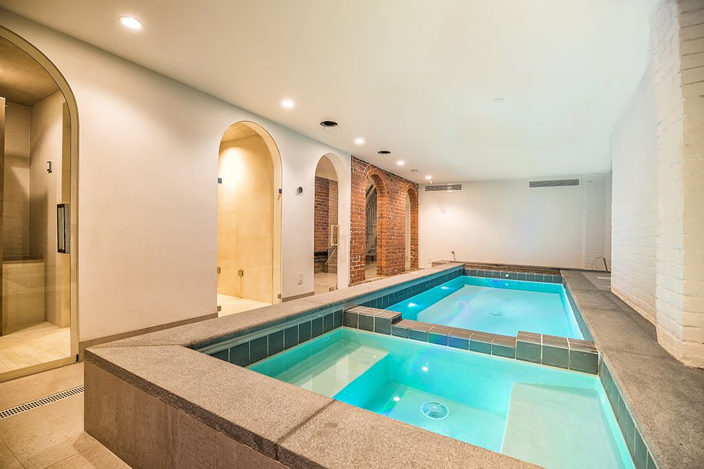 Indoor pool area with two pools, brick accents, and arched doorways.
