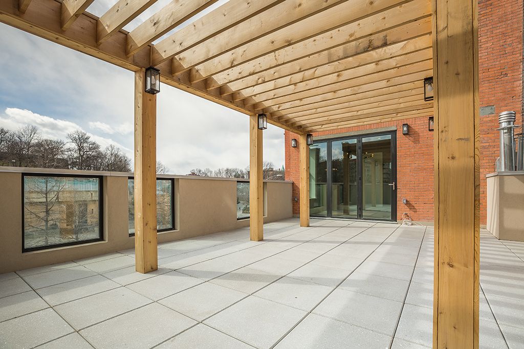Patio with wooden pergola and tiled floor, overlooking a cityscape.