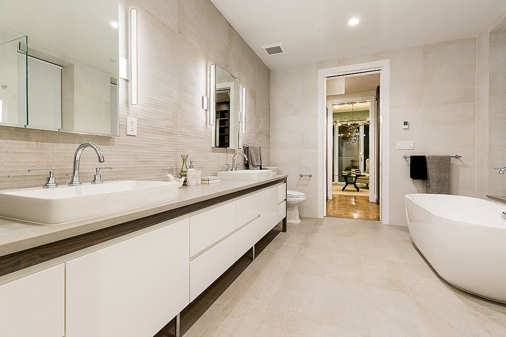 Modern bathroom with white cabinets, double sinks, and a freestanding tub.