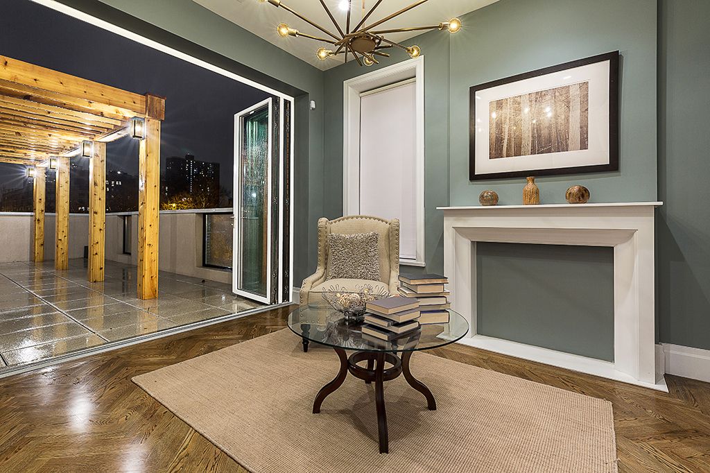 Cozy living room with open doors to a lit outdoor patio. A decorative chair sits near a glass table.