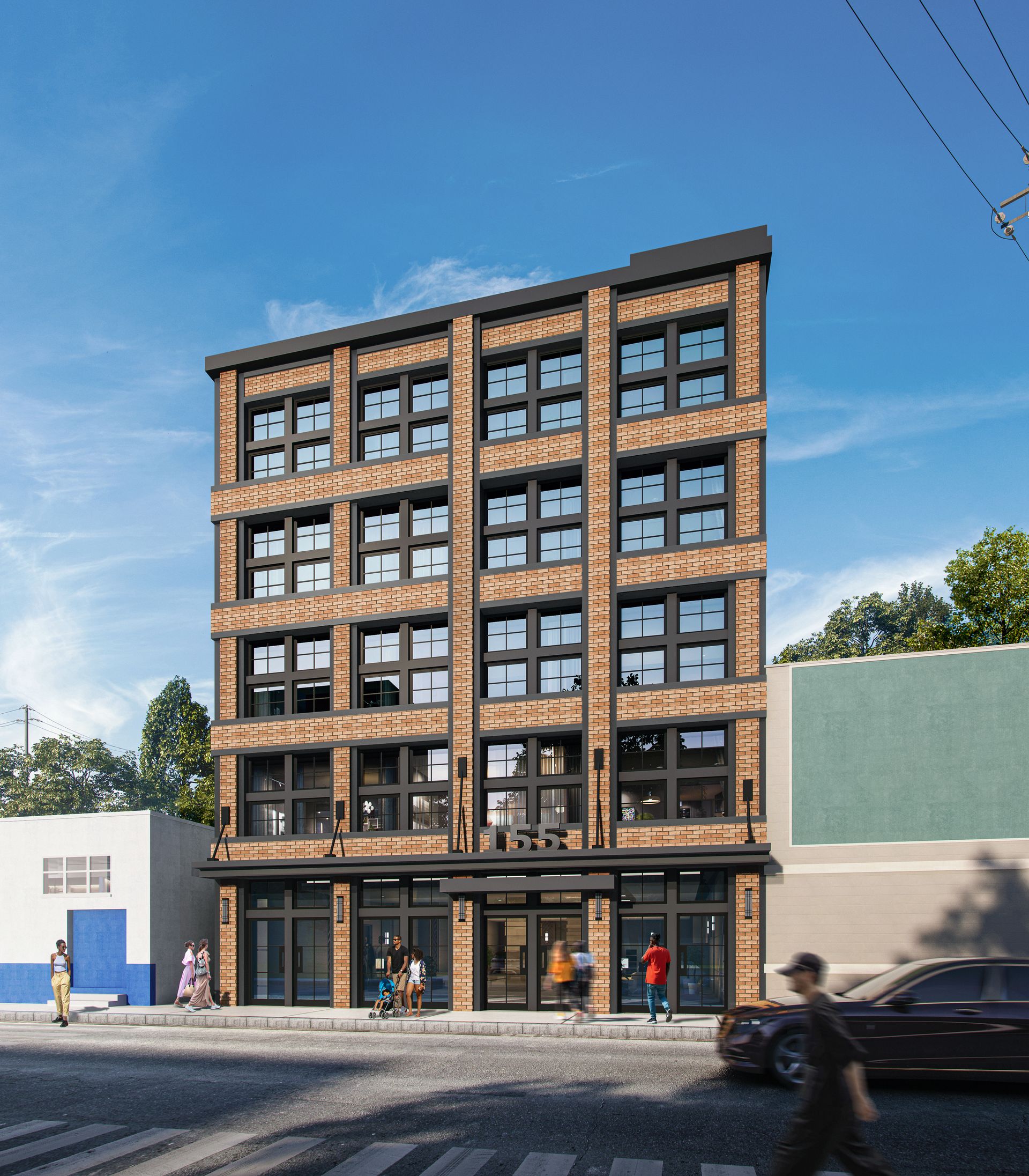 Brick building with dark framed windows, people walking on sidewalk. Street and blue sky.