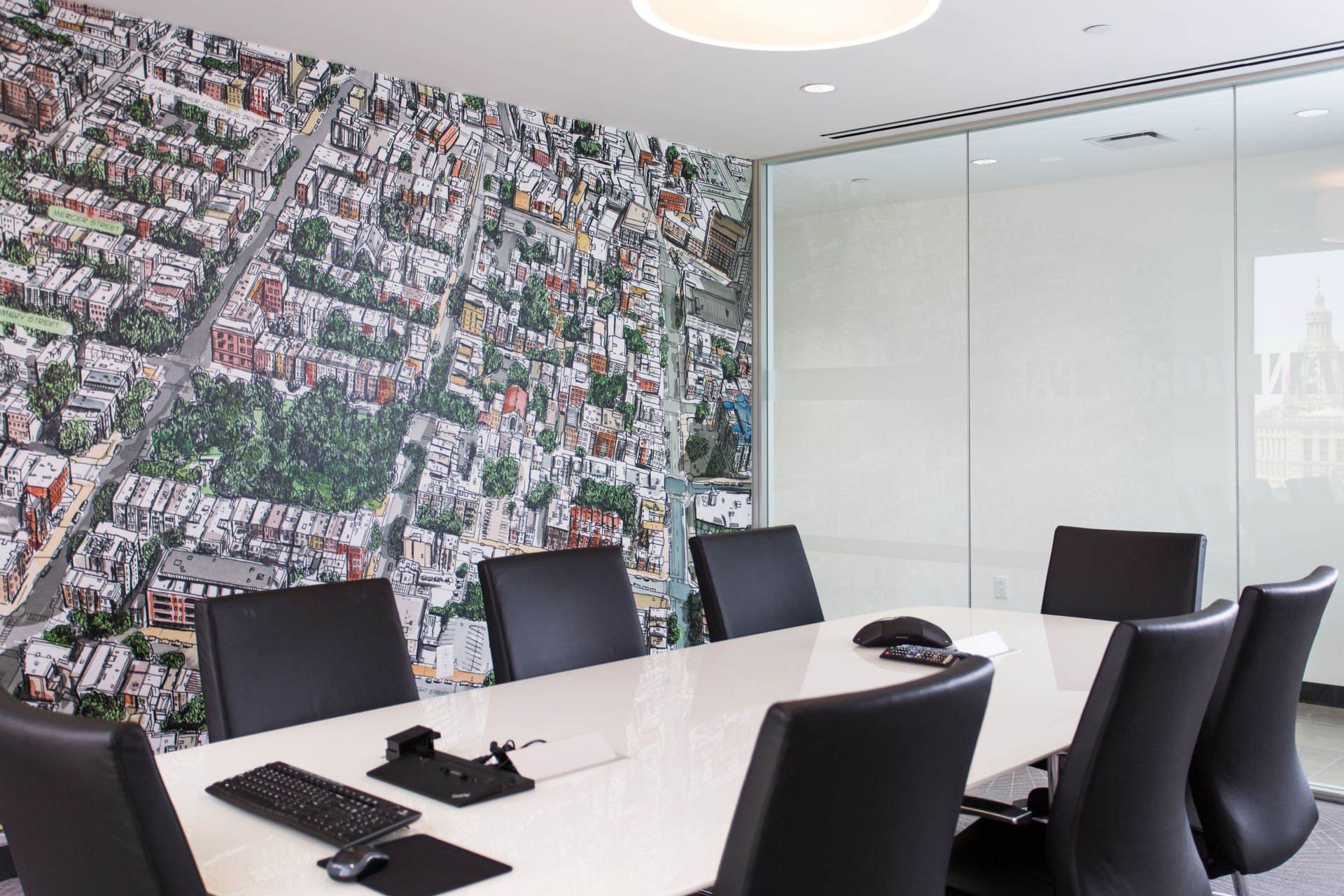 Conference room with a cityscape mural on the wall, oval white table, and black chairs.
