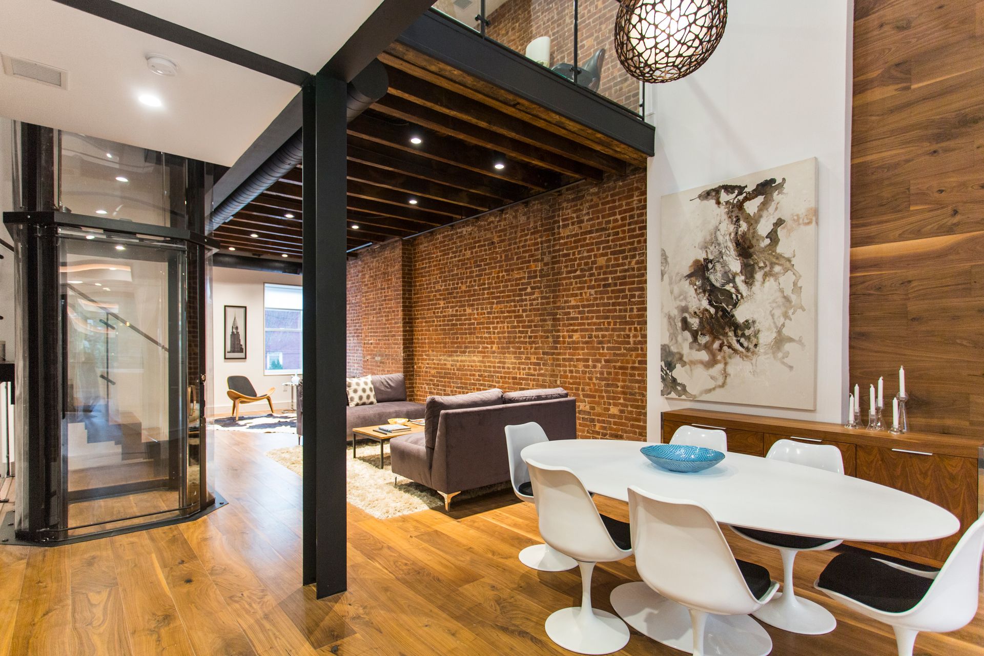 Modern apartment interior with exposed brick wall, dining area, and living area on the other side of the structure.