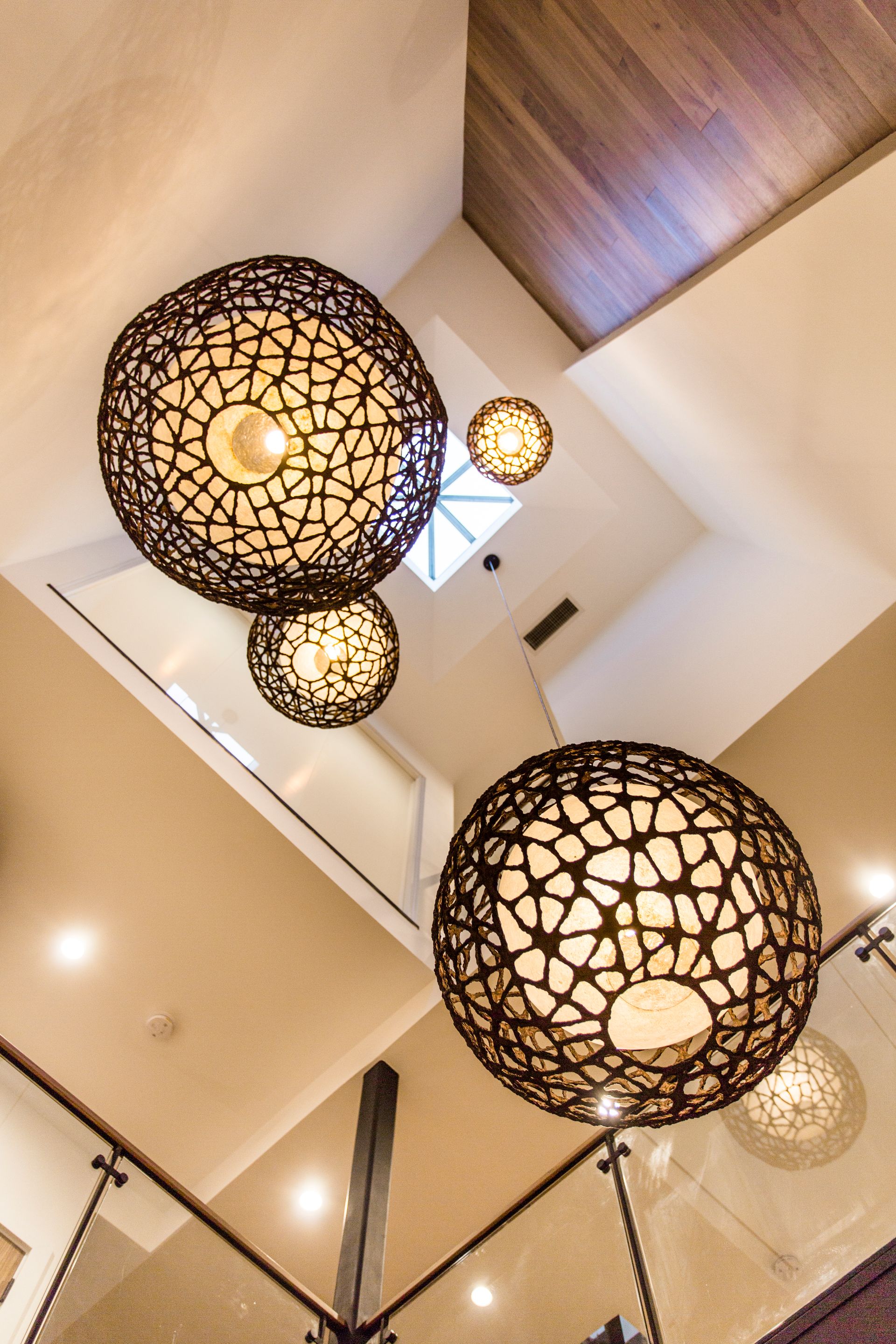 Large spherical pendant lights hanging from a high ceiling, with a staircase visible in the foreground.
