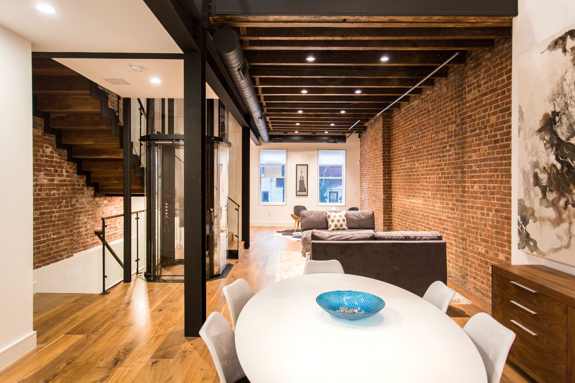 Modern home interior with exposed brick walls, hardwood floors, and a dining table.