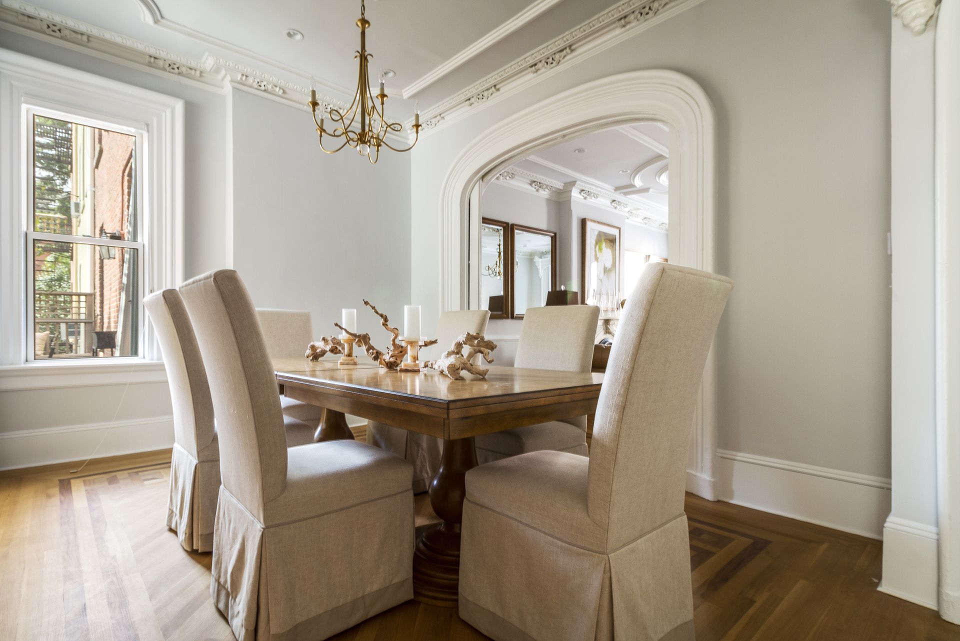 Elegant dining room with wooden table, upholstered chairs, and a large arched doorway.