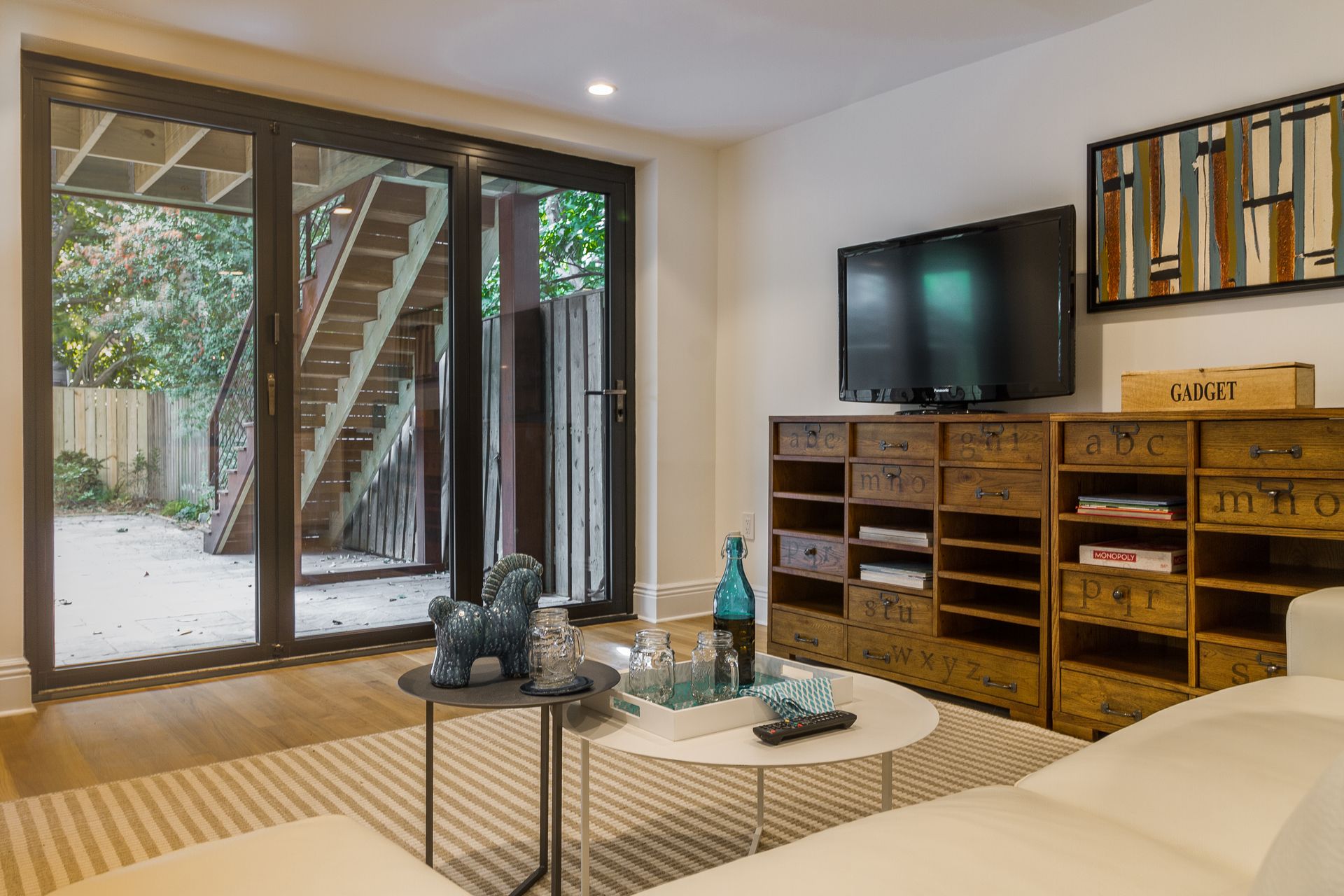 Living room with TV on wooden cabinets, glass doors to the backyard, and a small round coffee table.