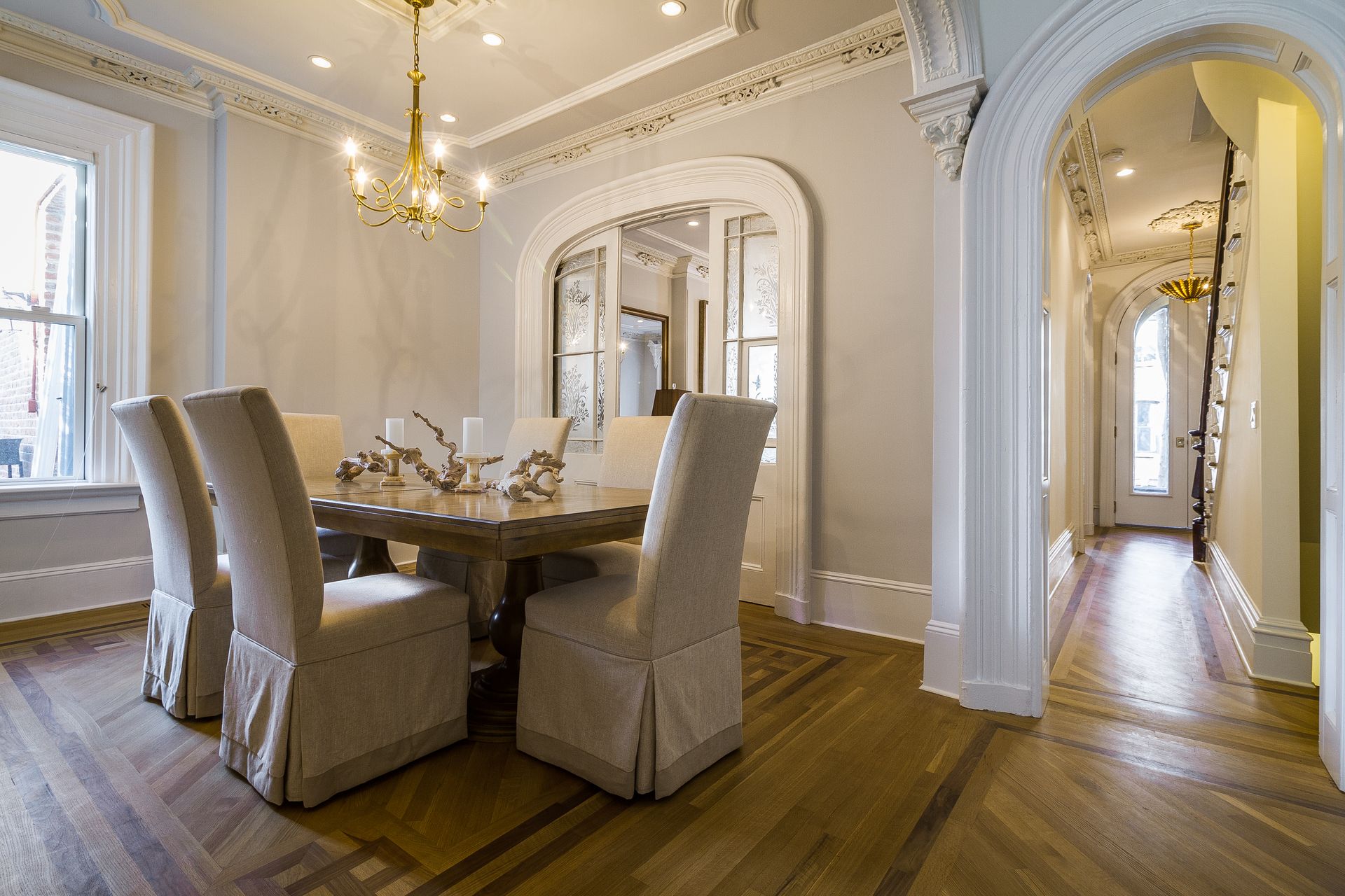 Elegant dining room with table and chairs, ornate molding, hardwood floor.