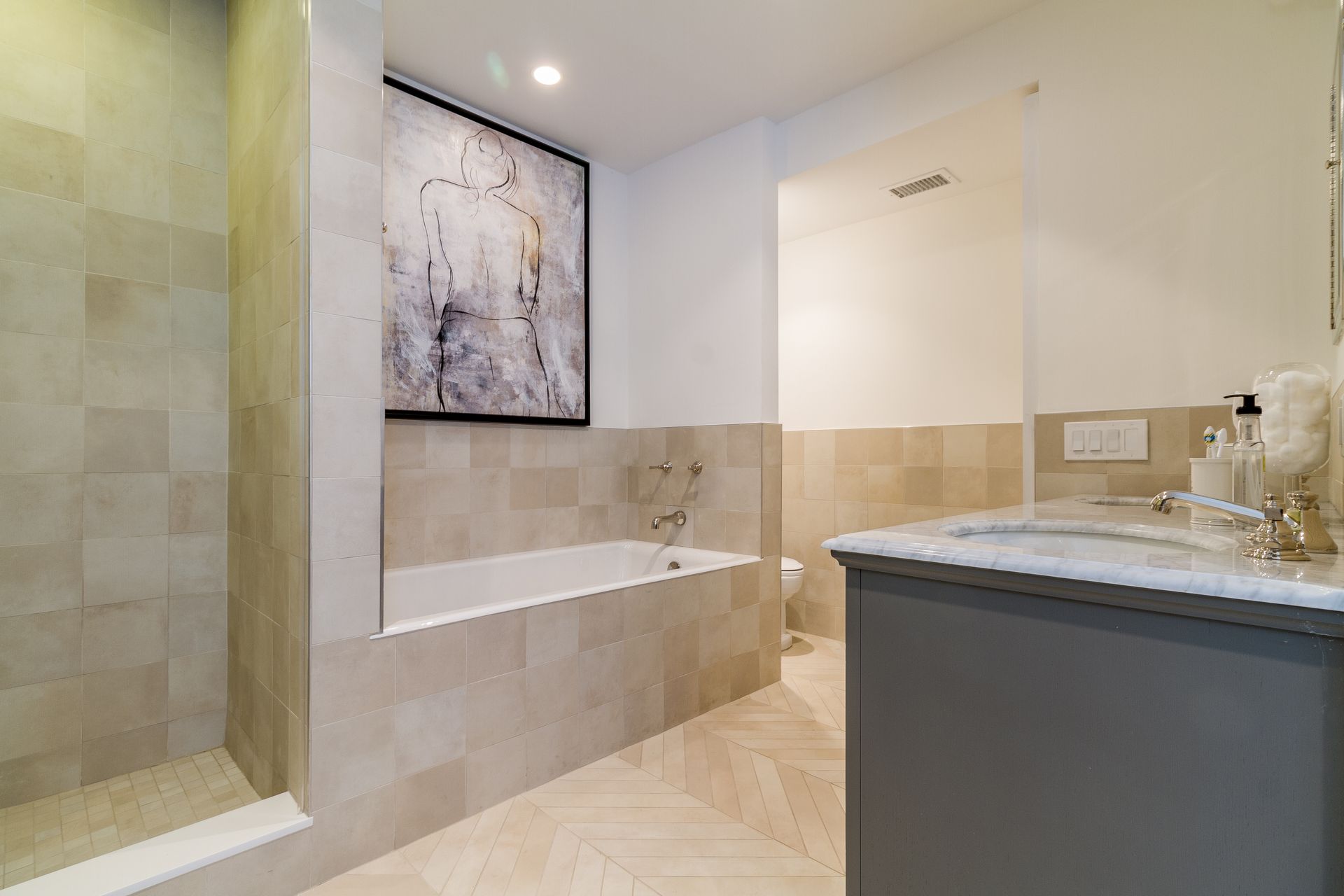 Bathroom with beige tiles, a bathtub, shower, and a gray vanity with a marble countertop.