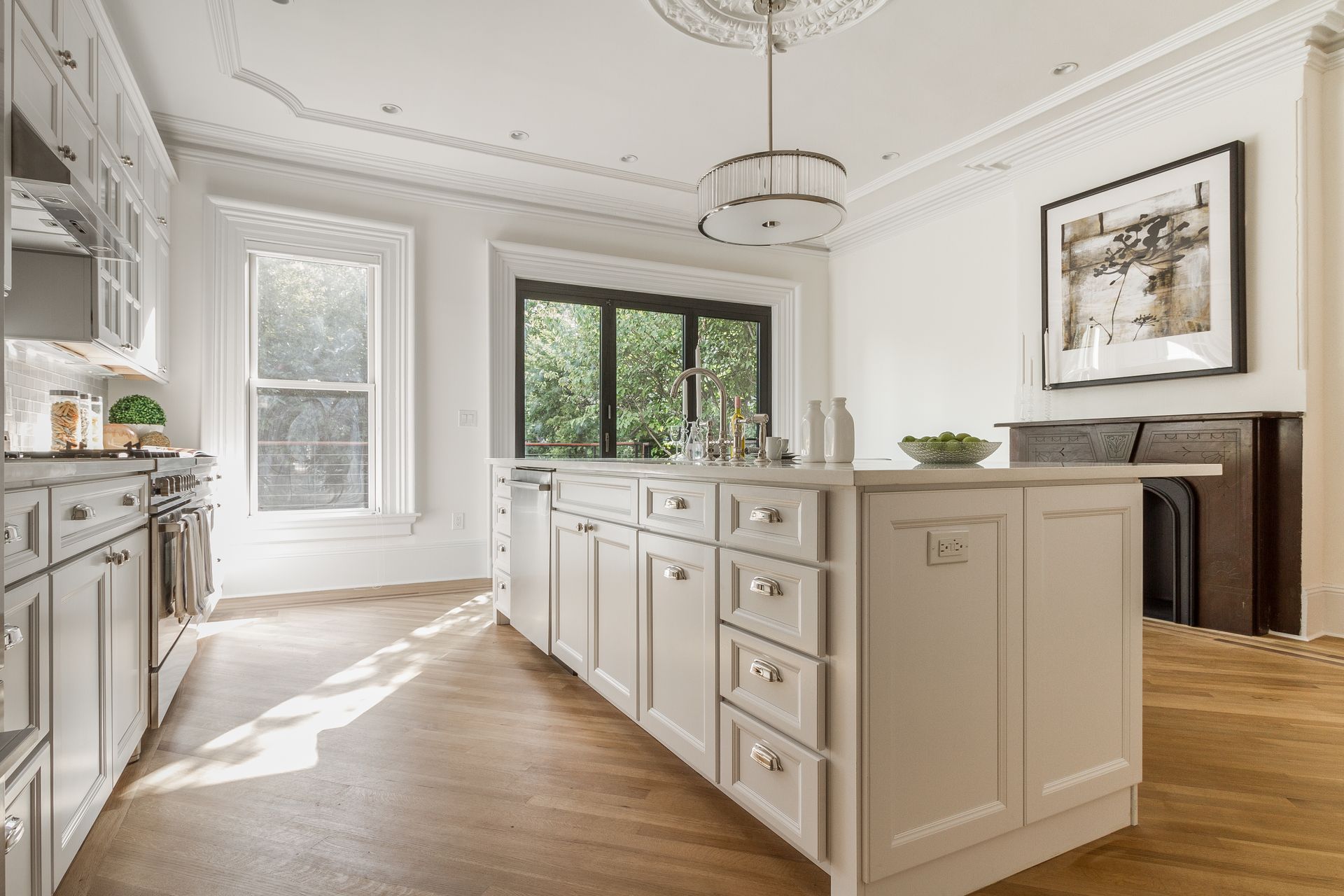 Bright white kitchen with island, cabinets, large windows, and decorative ceiling.