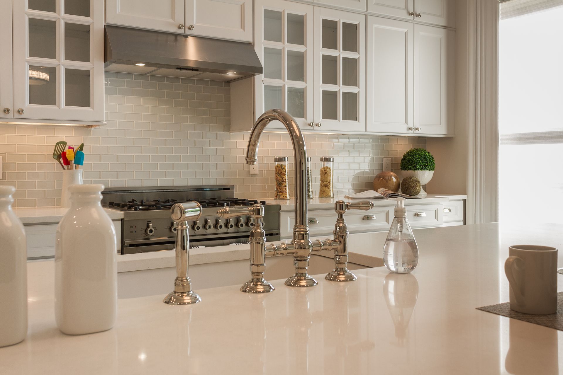 Modern kitchen with white cabinets, stainless steel faucet, and white countertops.