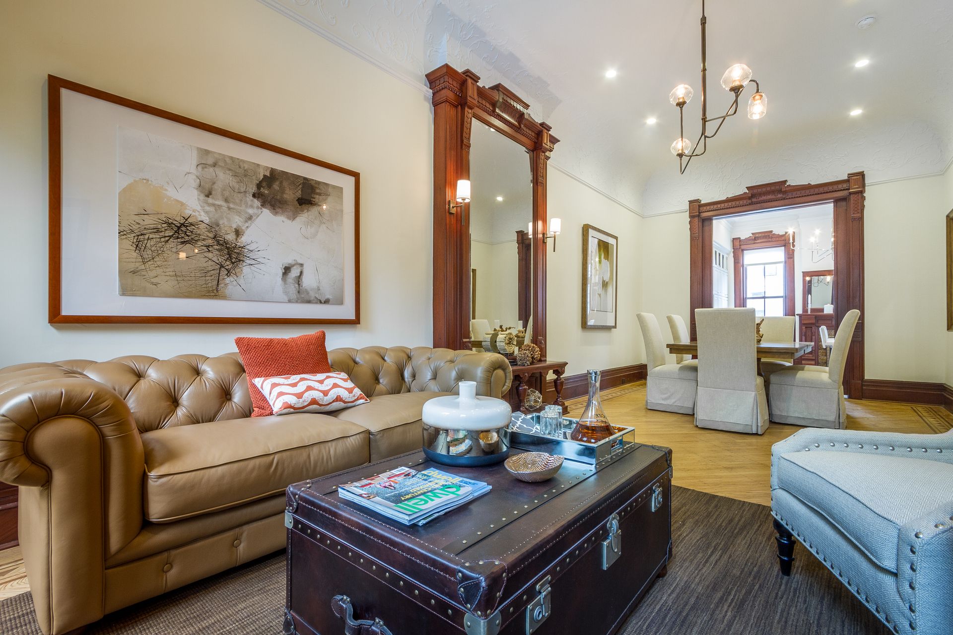 Living room with leather sofa, trunk coffee table, large mirror, and dining area visible.