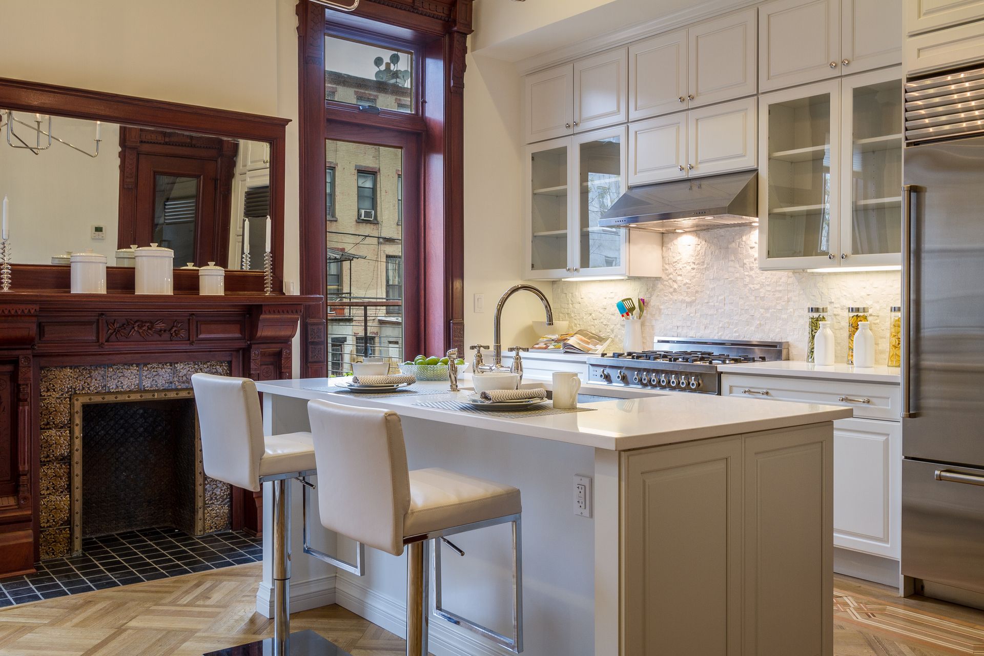 Kitchen with white cabinets, island, stove, and a dark wood fireplace.