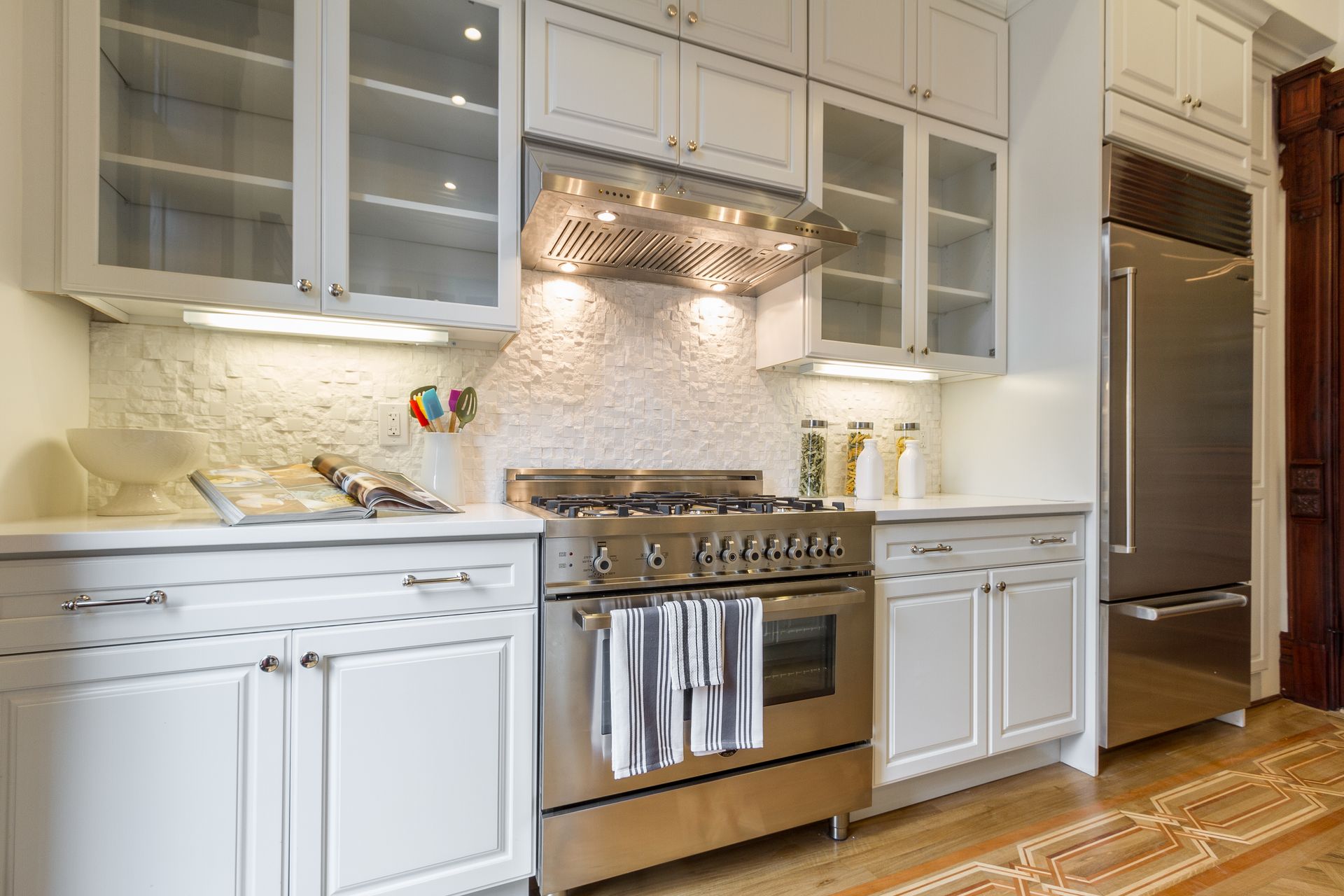 White kitchen with stainless steel appliances, cabinets, and a tile backsplash.