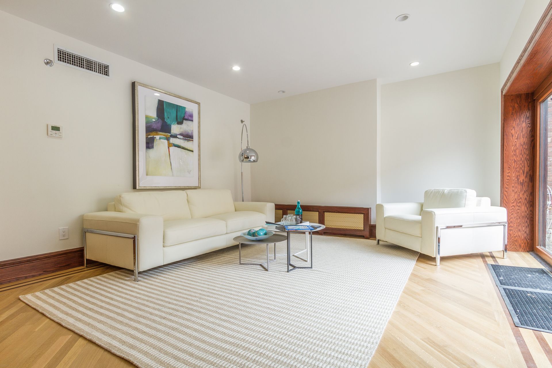 Living room with white sofa, armchair, rug, art, and coffee table.