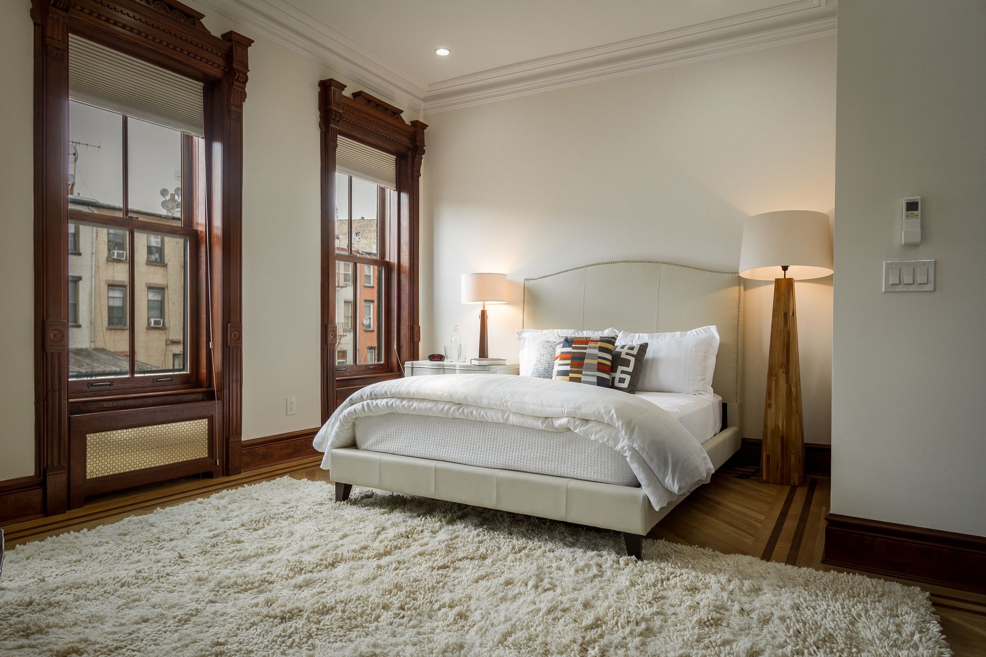 Bedroom with bed, large rug, windows, and lamps.