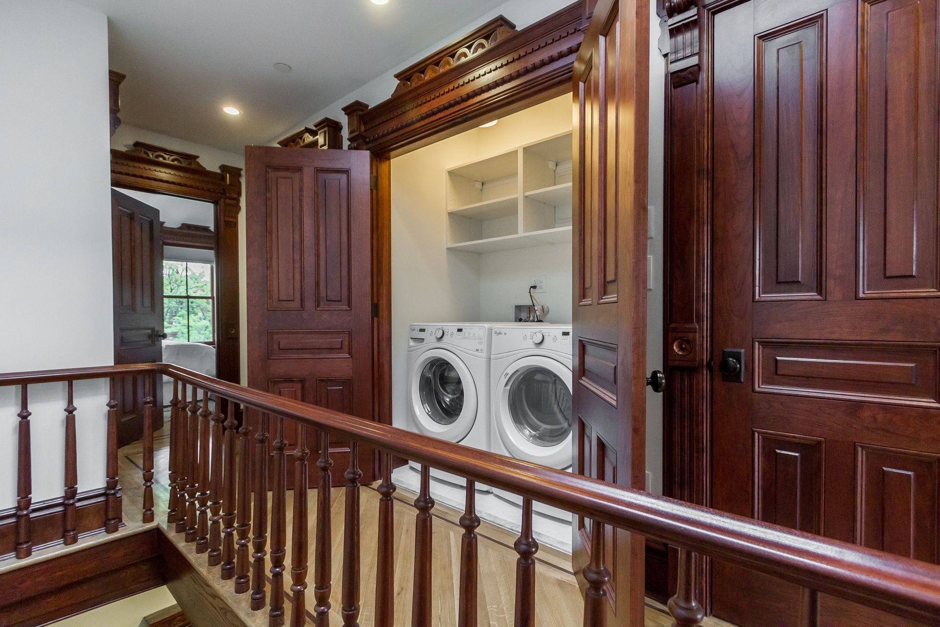 Laundry machines inside an open closet, brown wooden doors and trim.