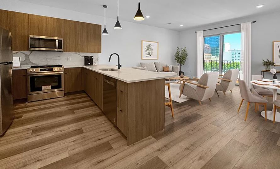 Modern kitchen and living room with wood cabinets, stainless steel appliances, and a balcony view.
