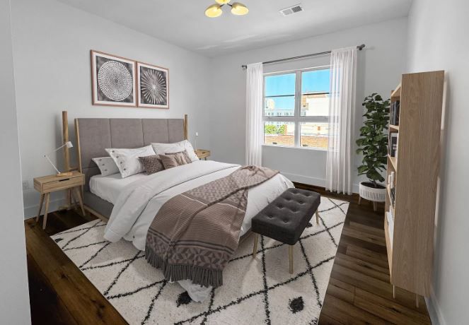 Bedroom with bed, rug, window, bookcase, and decorative art. Neutral tones, modern decor.