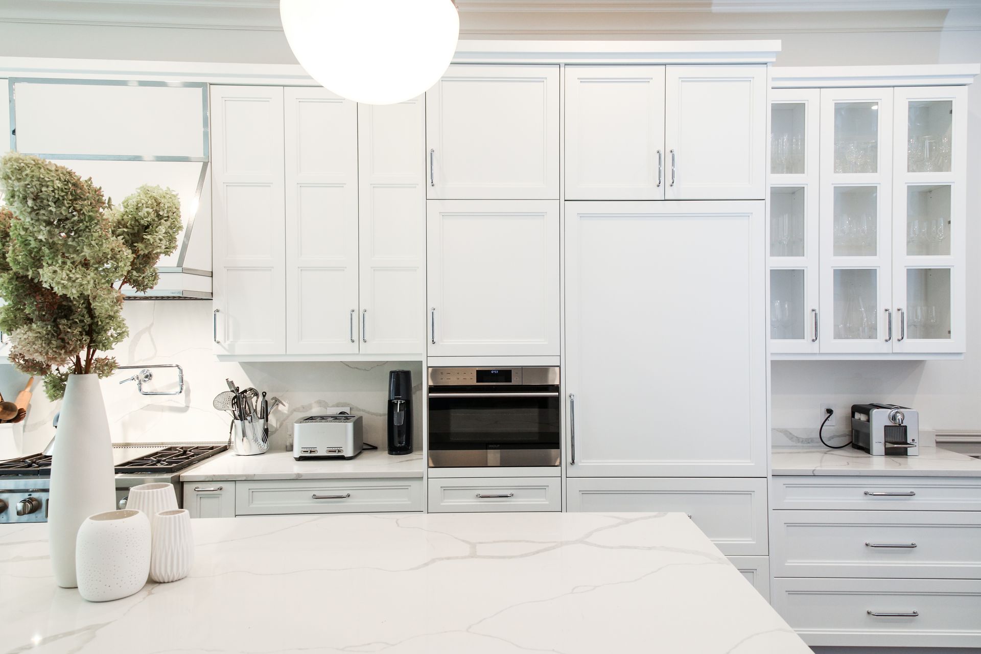 White kitchen with cabinets, island, and appliances, including a microwave and toaster.