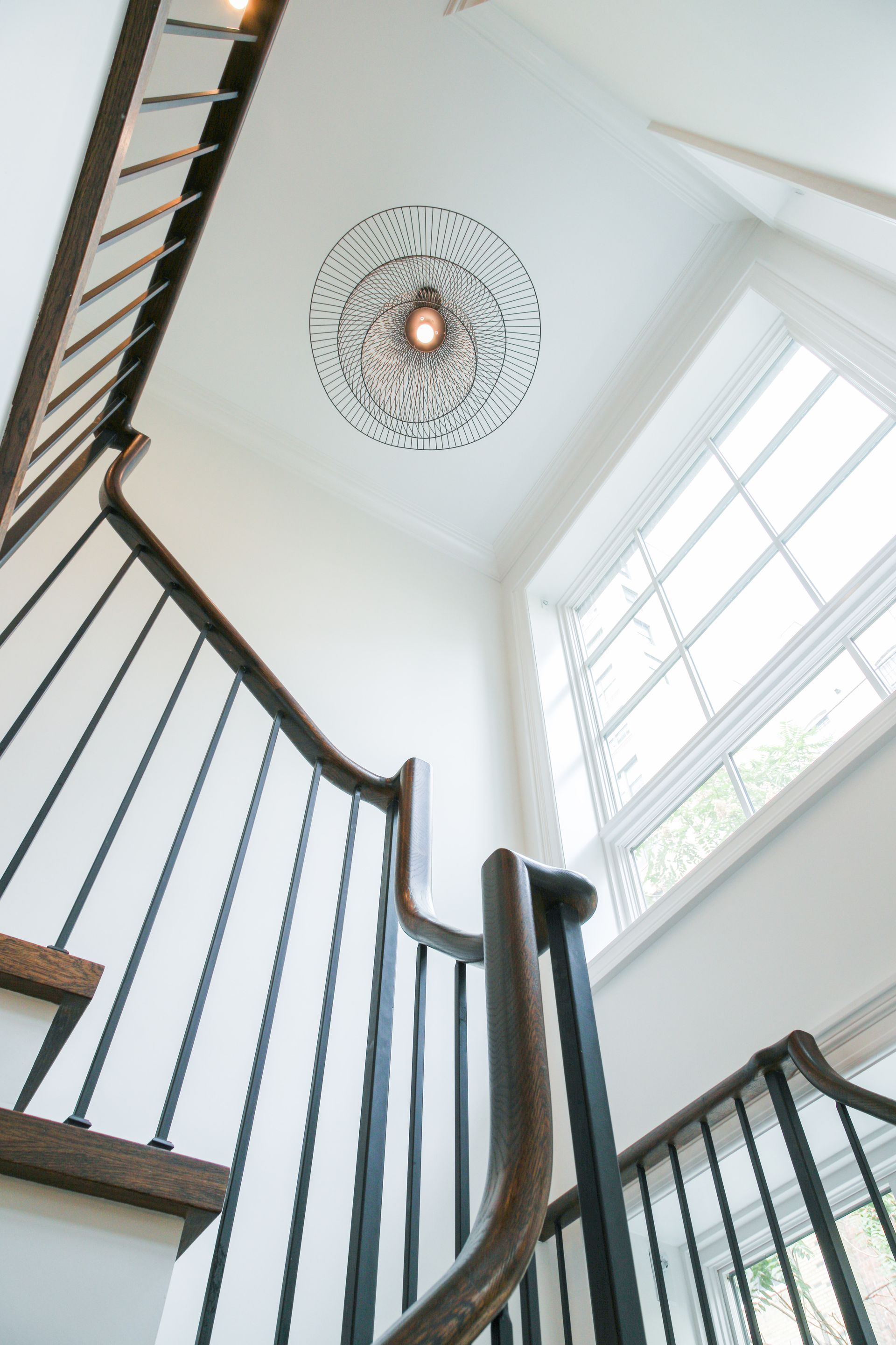 Staircase with dark wooden handrail, black spindles, and a ceiling medallion with light fixture.