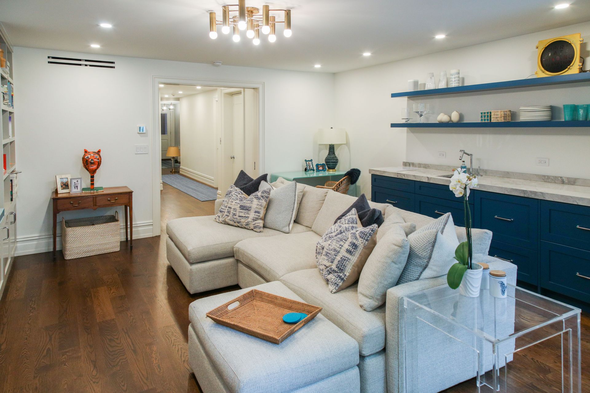 Living room with cream sectional, blue cabinets, and dark wood floor.