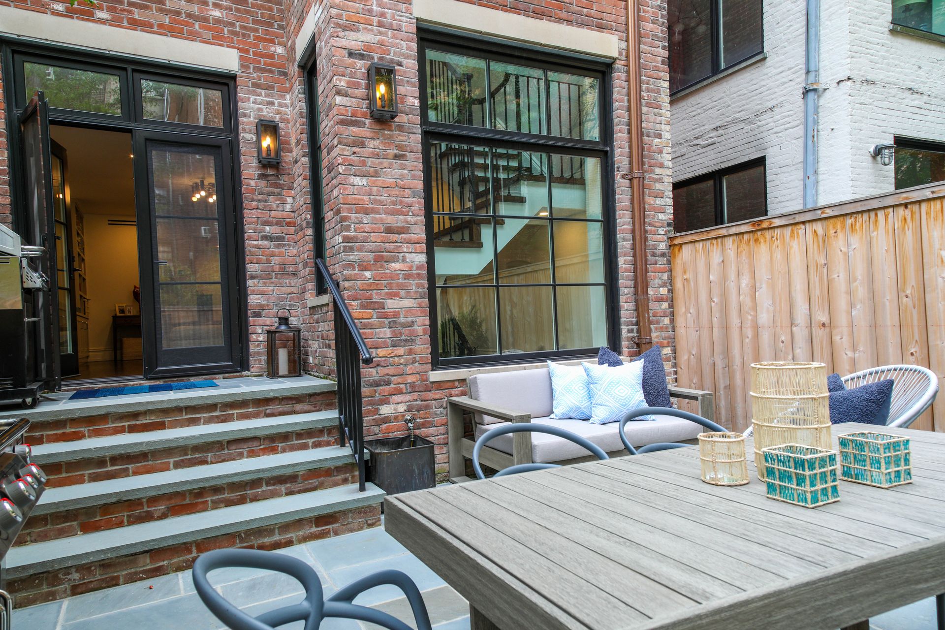 Patio with brick building, outdoor seating, wooden fence.
