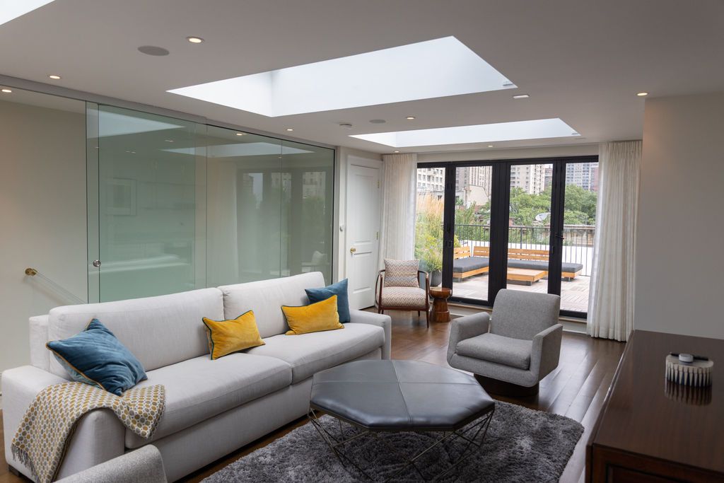 Living room with white sofa, gray armchair, and dark wood floors, opens to a patio.