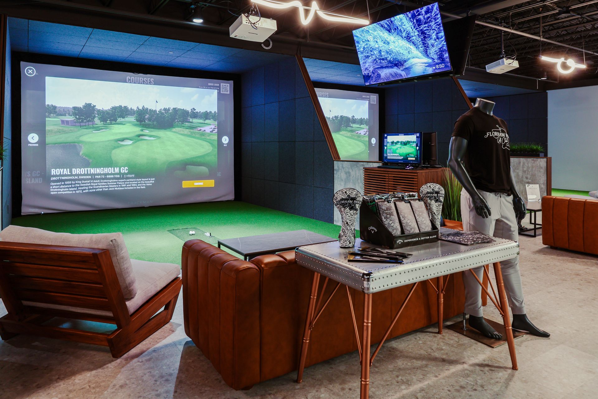 Indoor golf simulator with screens, lounge seating, and golf equipment.