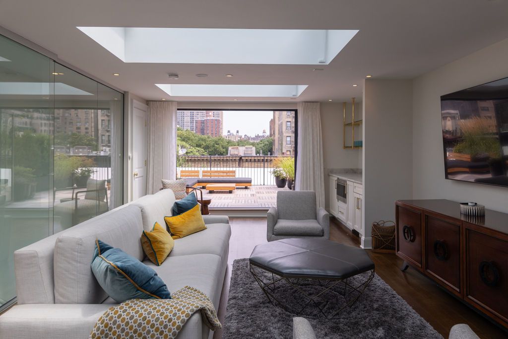 Living room with white sofa, blue and yellow pillows, and a view of a terrace.