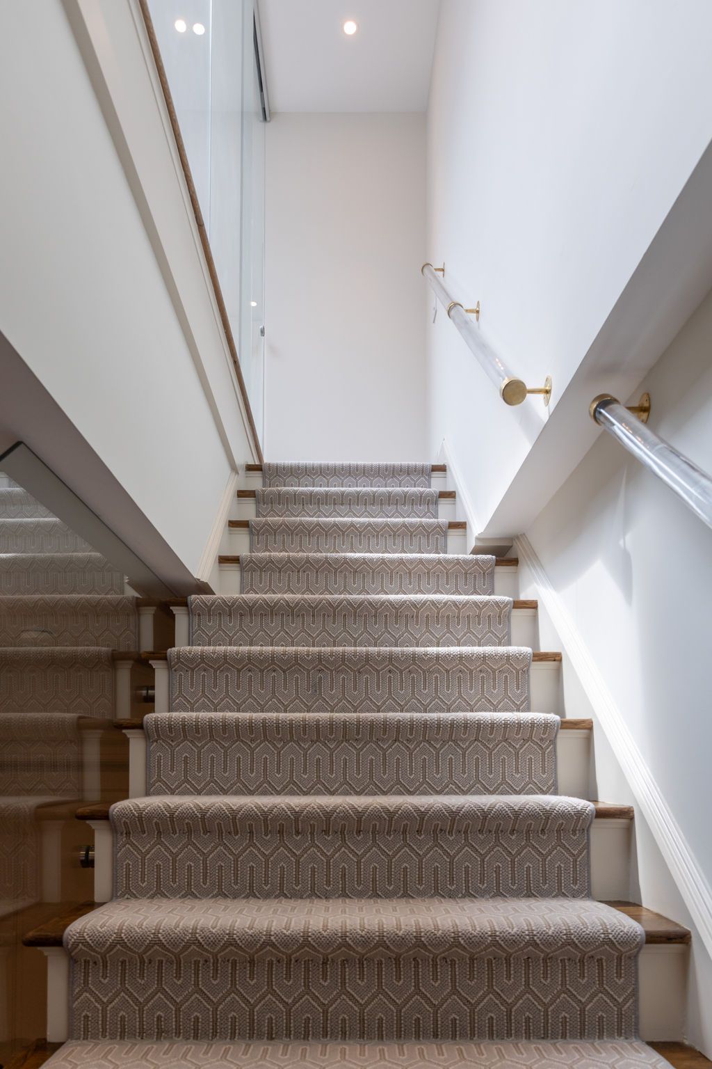Carpeted staircase with white walls and a glass railing.