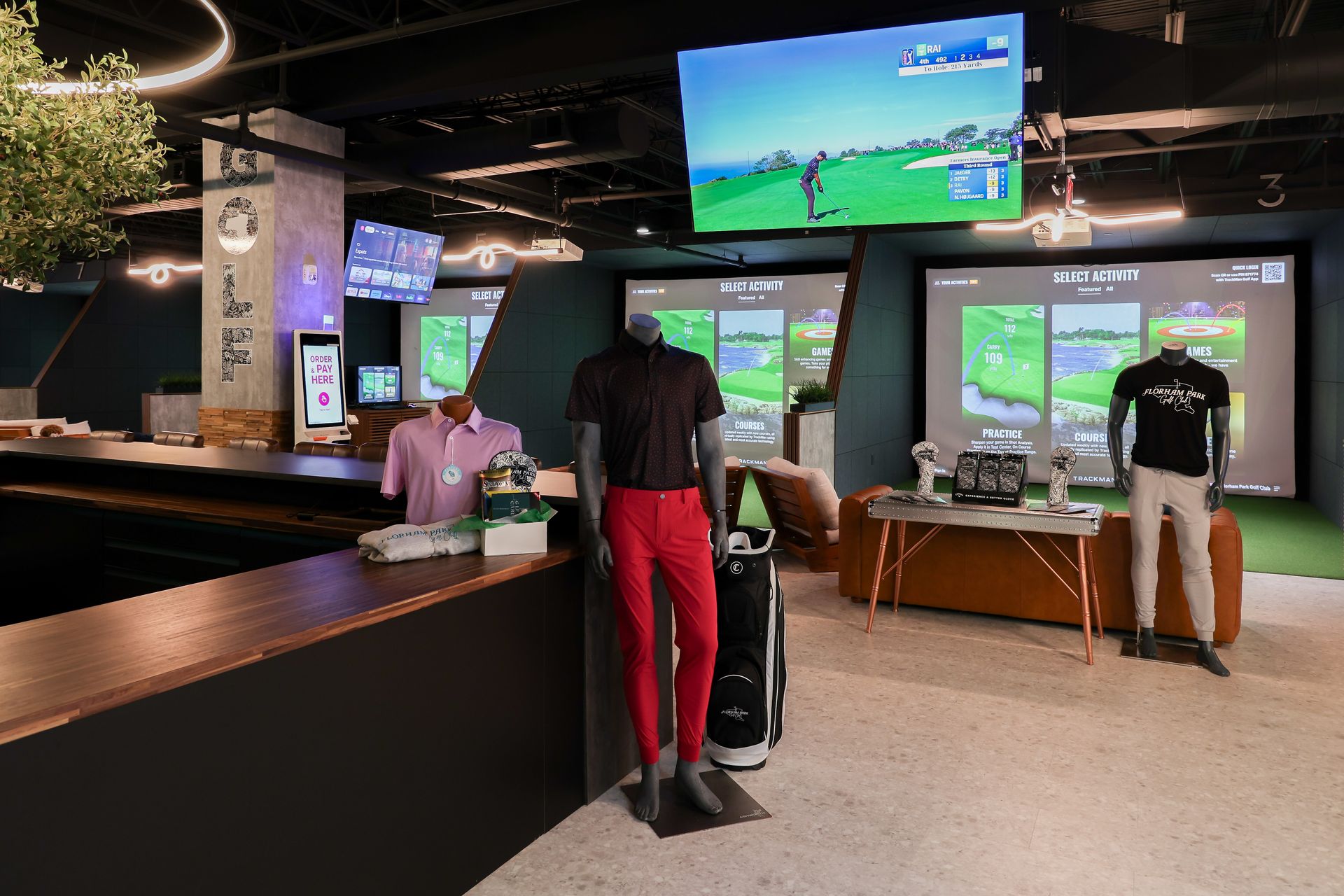 Indoor golf simulator with screens, mannequins, golf equipment, and a bar area.