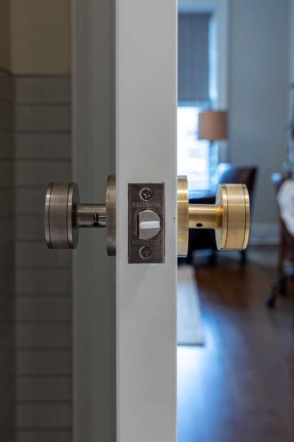 Door with two different textured doorknobs, one silver, one gold, on a white door.