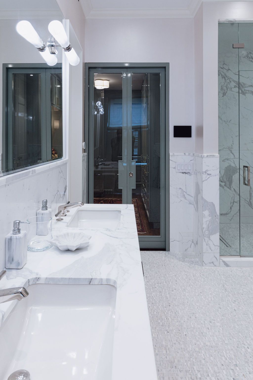 Luxurious white marble bathroom with double sinks and shower.
