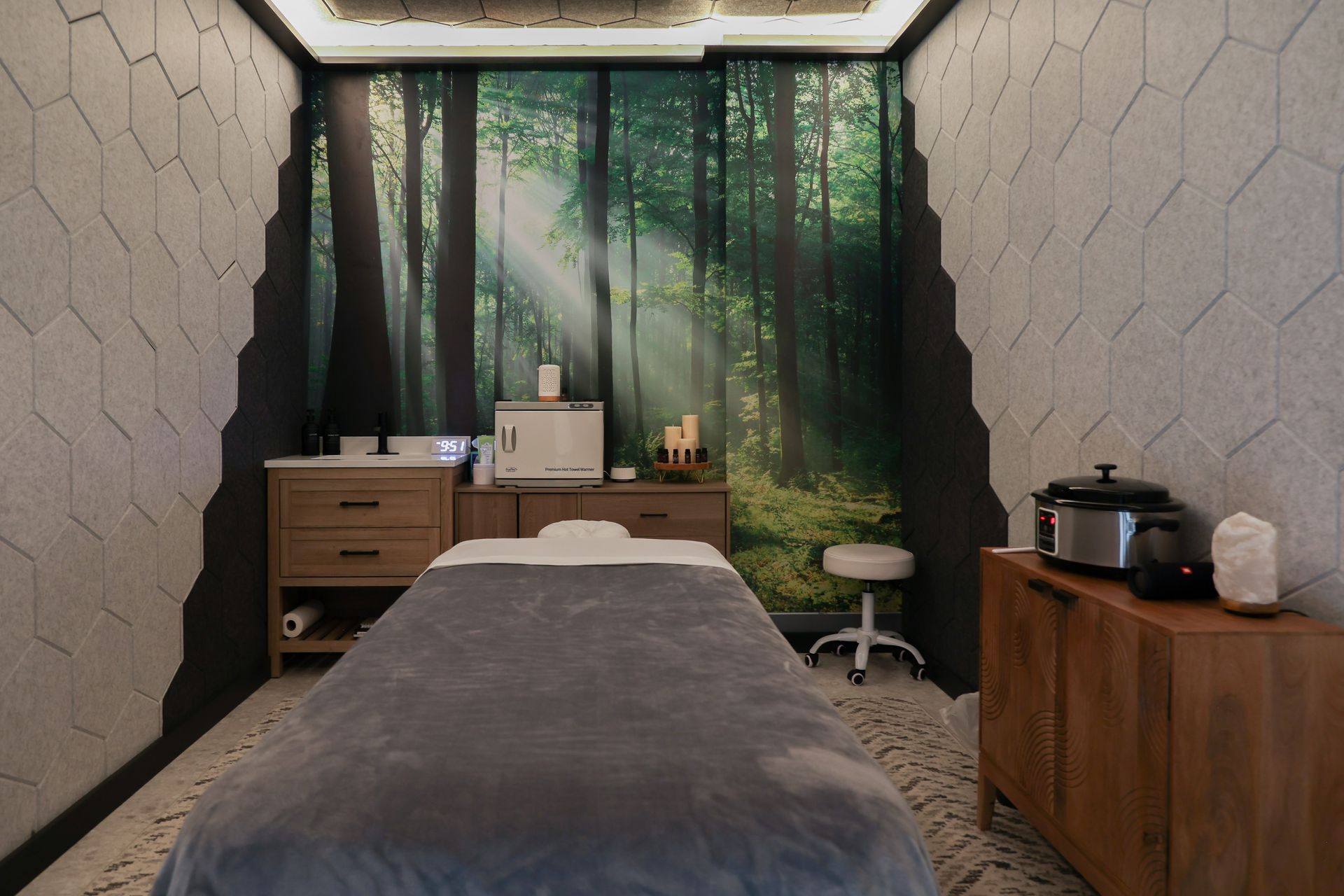 Massage room with a forest mural, massage table, and wooden furniture.