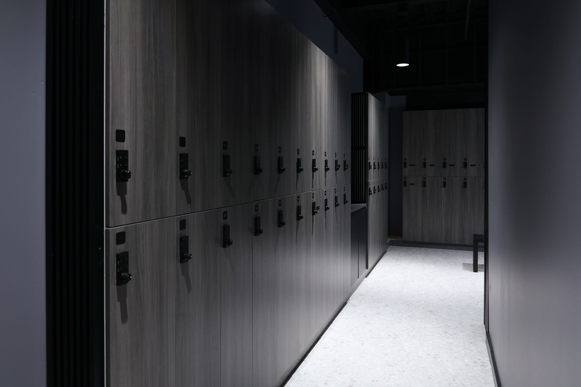 Locker room interior with rows of dark wood lockers along a hallway.