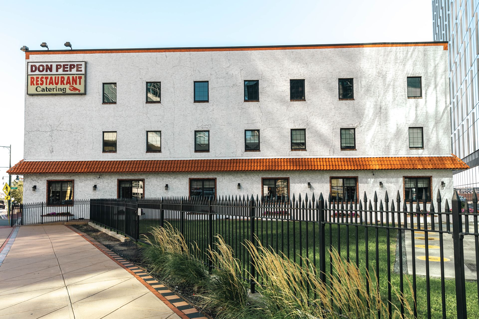 Dom Pepe Restaurant, white brick building with black windows, red tile roof, and a black fence.