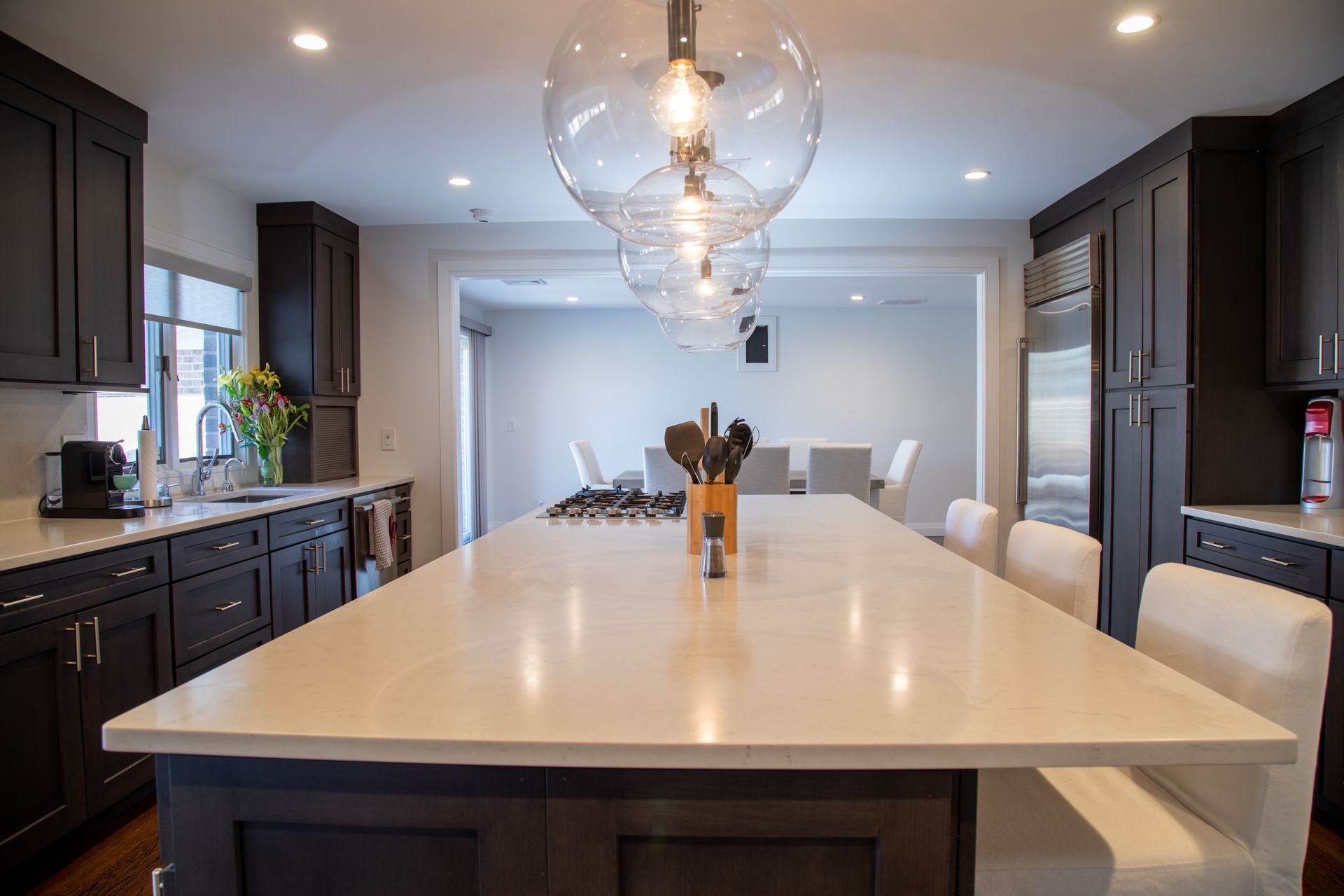 Modern kitchen with dark cabinets, a large island, and globe pendant lights.