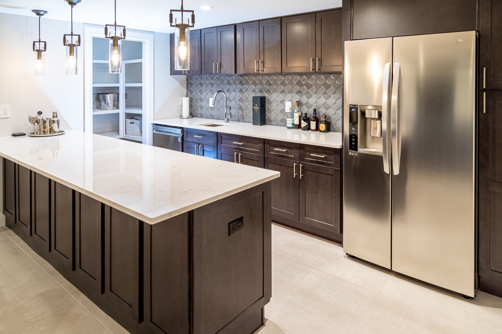 Modern kitchen with dark brown cabinets, white countertops, stainless steel fridge, and an island.