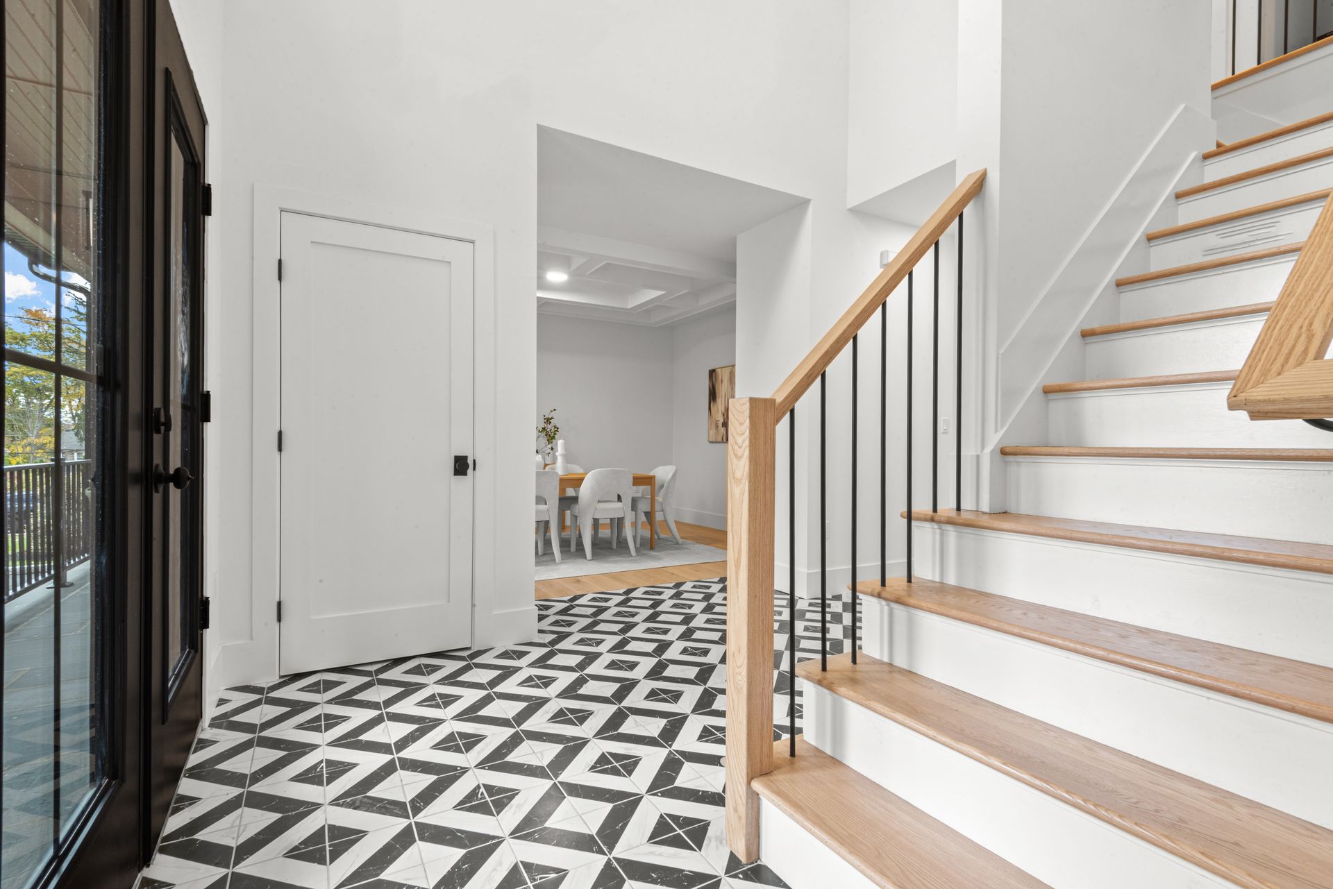 Entryway with patterned floor, staircase, and doorway leading to dining area.