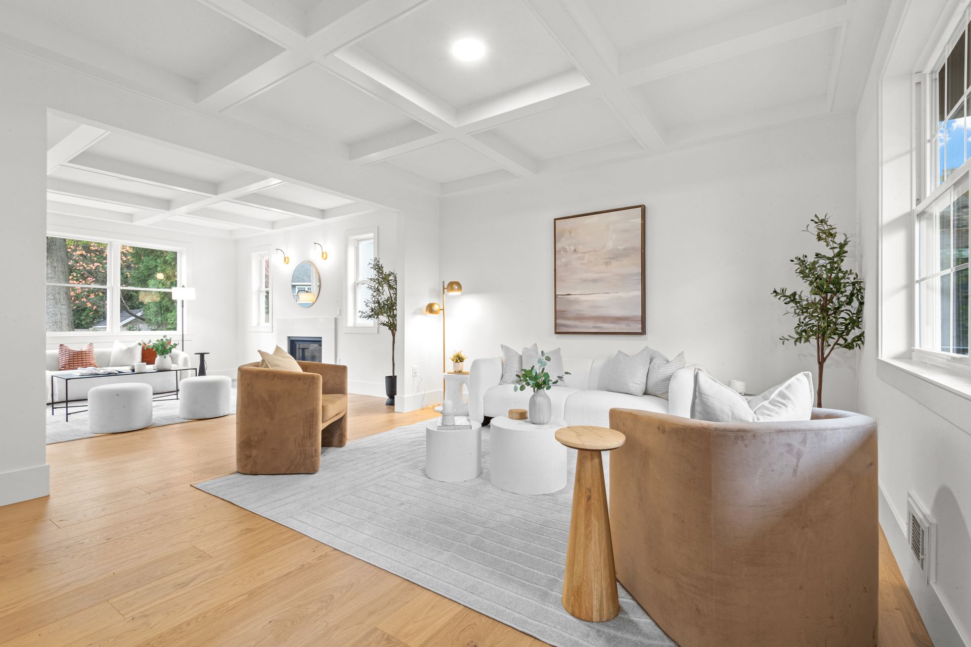 Bright living room with white walls, coffered ceiling, wood floors, and neutral furniture.
