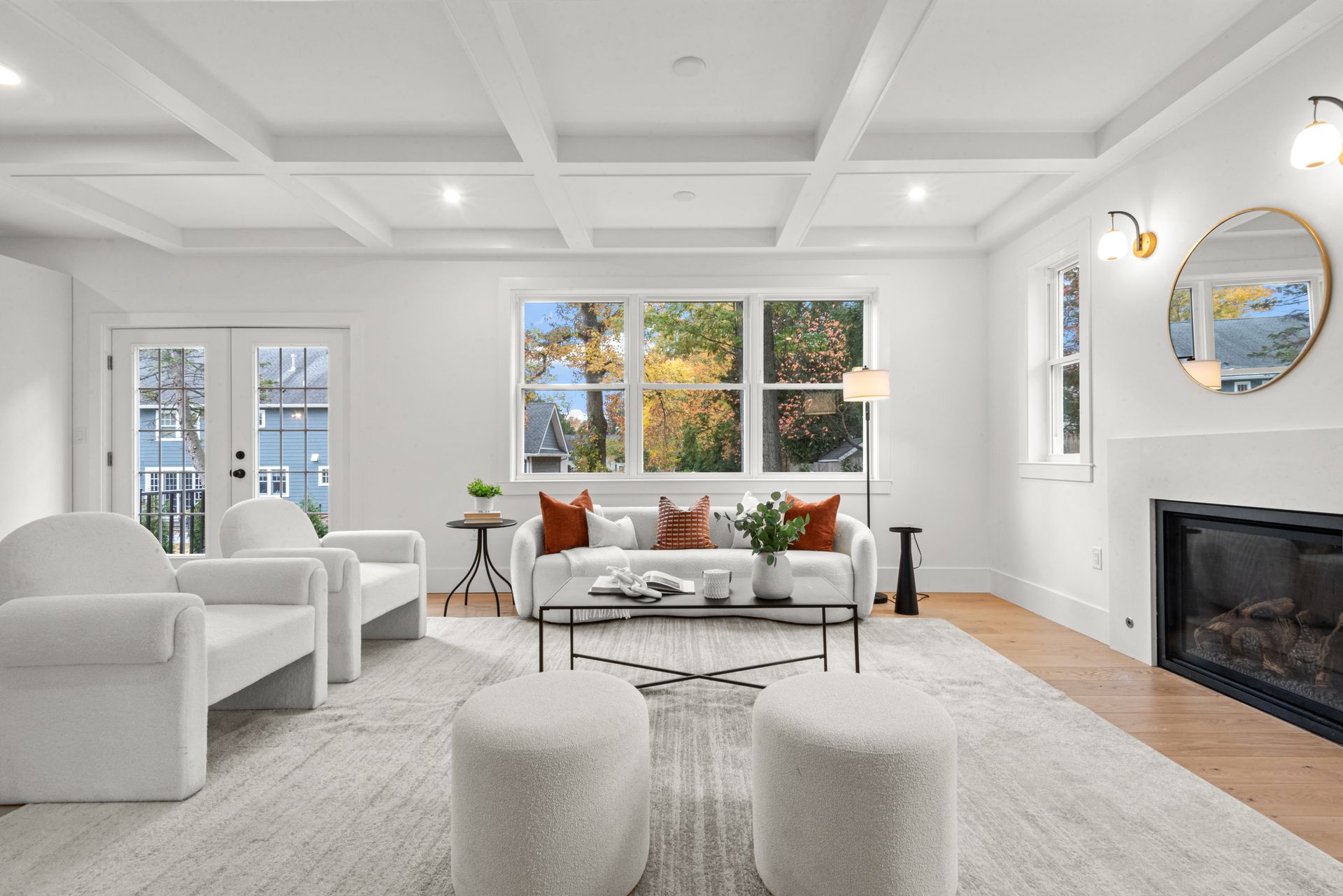 Bright living room with white furniture, fireplace, large windows, and a coffered ceiling.