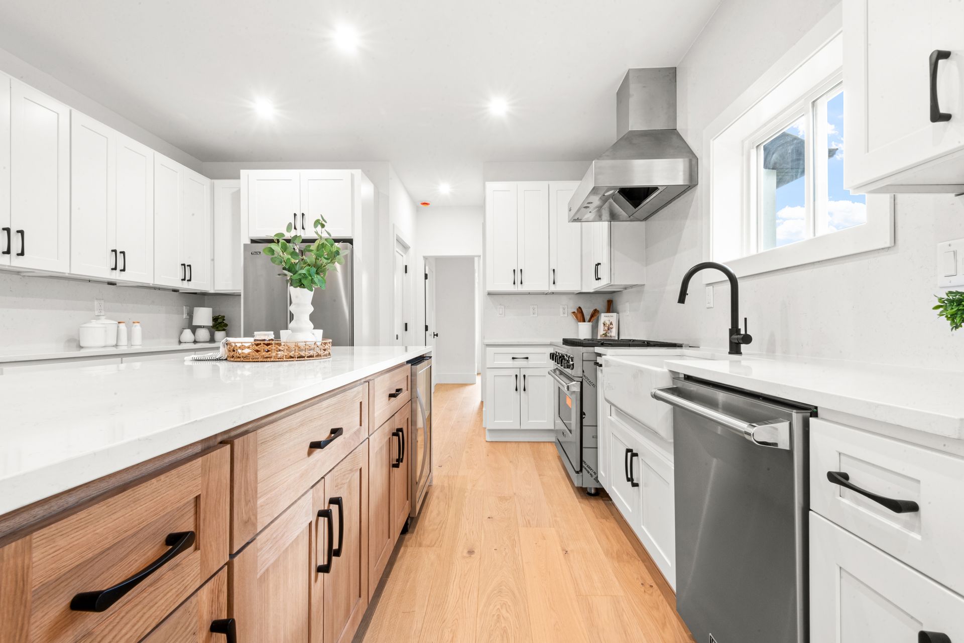 Modern kitchen with white cabinets, wood island, stainless steel appliances, and wood flooring.