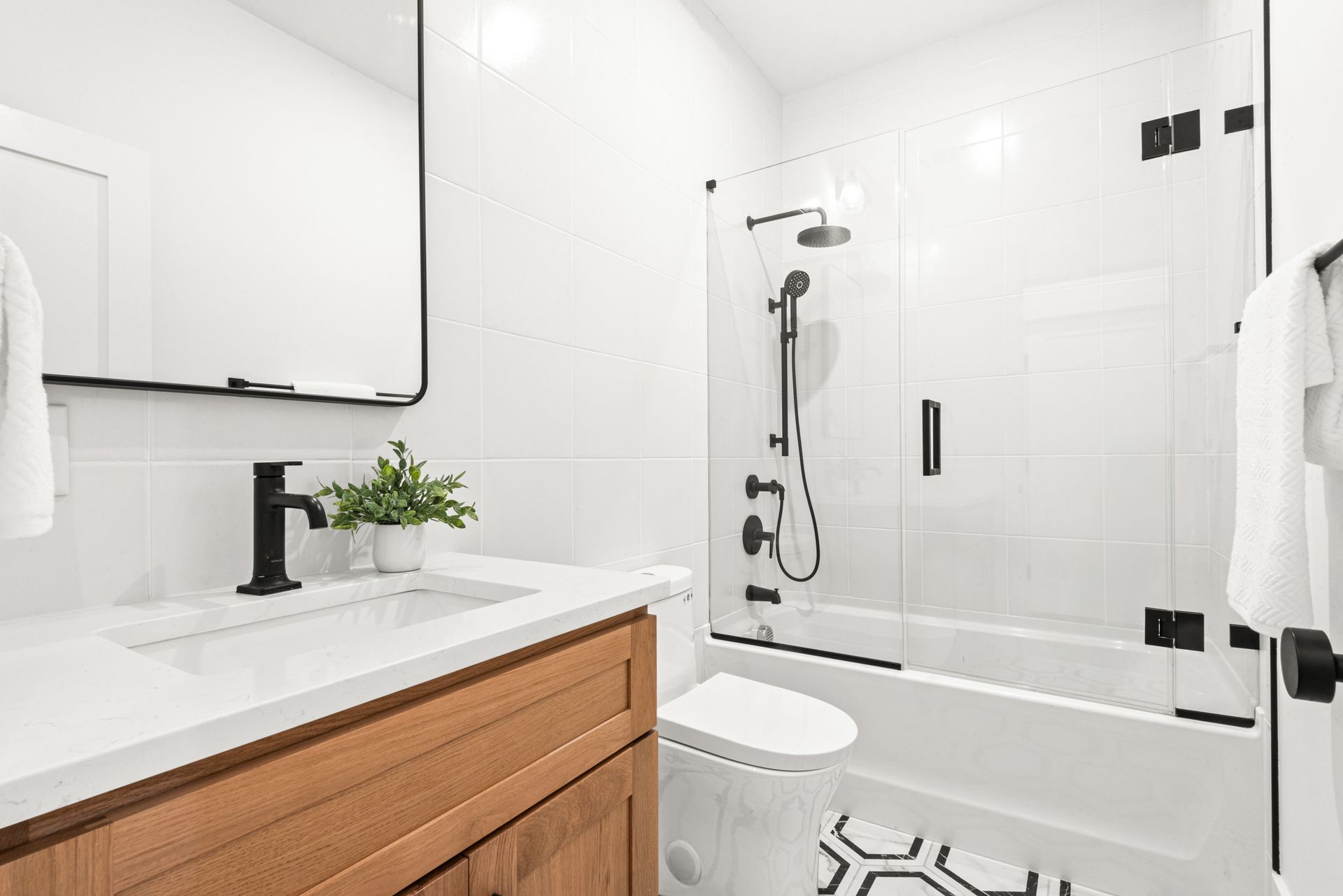 Modern bathroom with white walls, wood vanity, and black fixtures.