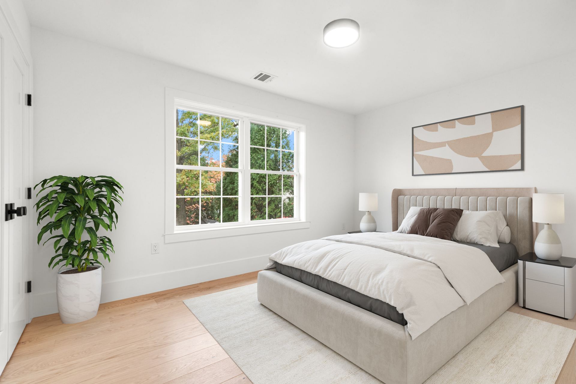 Bedroom with bed, rug, window, plant, artwork, and nightstands.